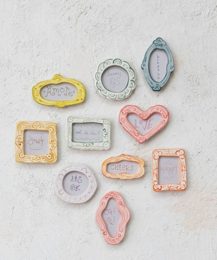Set of small decorative picture frames in pastel colors on a textured white surface