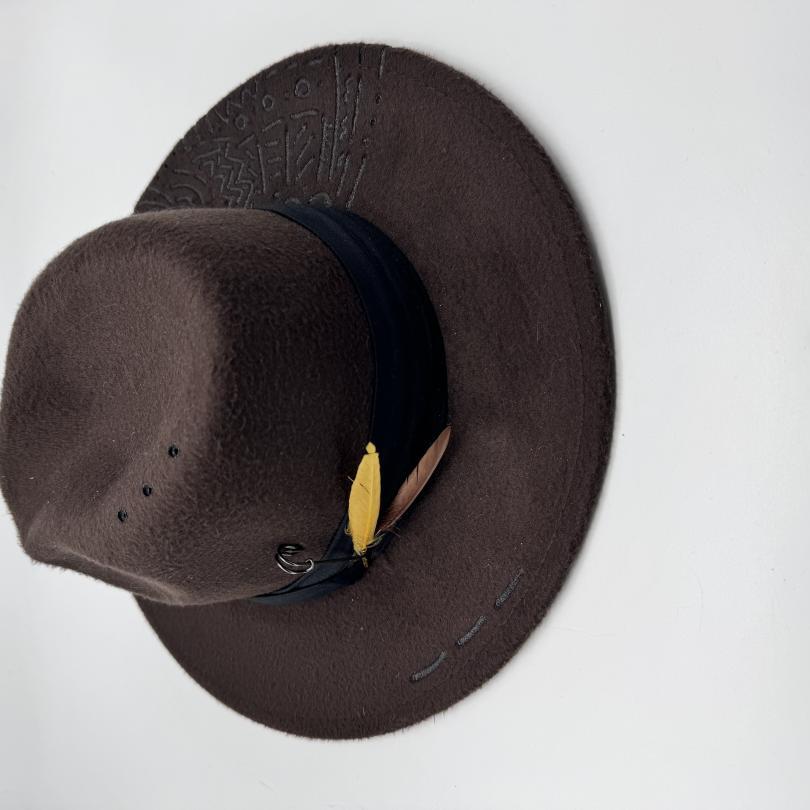 Dark brown fedora with hand carving and feathers