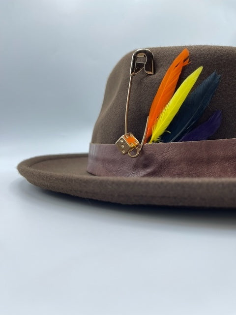 Brown fedora hat accessorized withe feathers and golden brooch